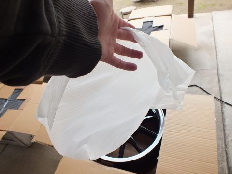 2003 Ford Crown Victoria - White foam packaging being pulled off a black-spoke alloy wheel set in a cardboard box