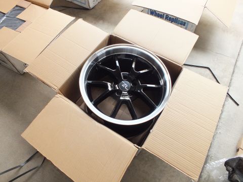 2003 Ford Crown Victoria - Eight-spoke gloss black alloy wheel with machined lip sitting in a box beside a Wheel Replicas carton