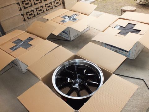 2003 Ford Crown Victoria - One black machined-lip alloy wheel in a box at center of several open empty cartons outdoors