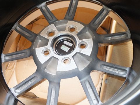 2003 Ford Crown Victoria - Detail of a gunmetal alloy wheel face with machined spokes, five lug holes and a green label