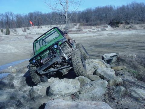 1992 Ford Bronco - A green Suzuki Samurai tackles a challenging rock obstacle during an off-road excursion.