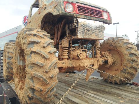 1986 Ford Bronco - This heavily modified truck is covered in mud, suggesting recent off-road use.