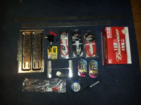 1986 Ford Bronco - Various automotive parts and a box of Budweiser are arranged on a dark, carpeted surface.