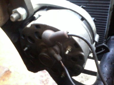 1981 Ford Bronco - Close-up view of an alternator, showing a spark plug wire connected to its housing.