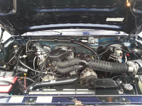 1995 Ford Bronco - Engine bay of a 1995 Ford Bronco, viewed from above with the hood raised.