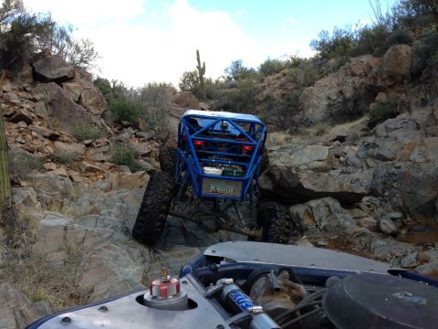 1966 Ford Bronco - Two off-road vehicles navigate a challenging rocky trail in a desert landscape.