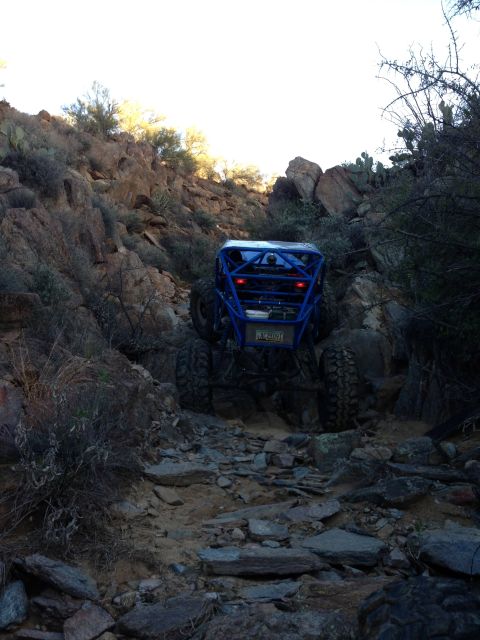 1966 Ford Bronco - A custom blue off-road buggy navigates a challenging rocky path in a desert environment.