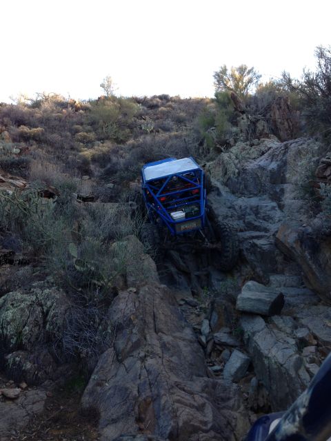 1966 Ford Bronco - A custom blue off-road buggy tackles a challenging rocky incline in a desert landscape.