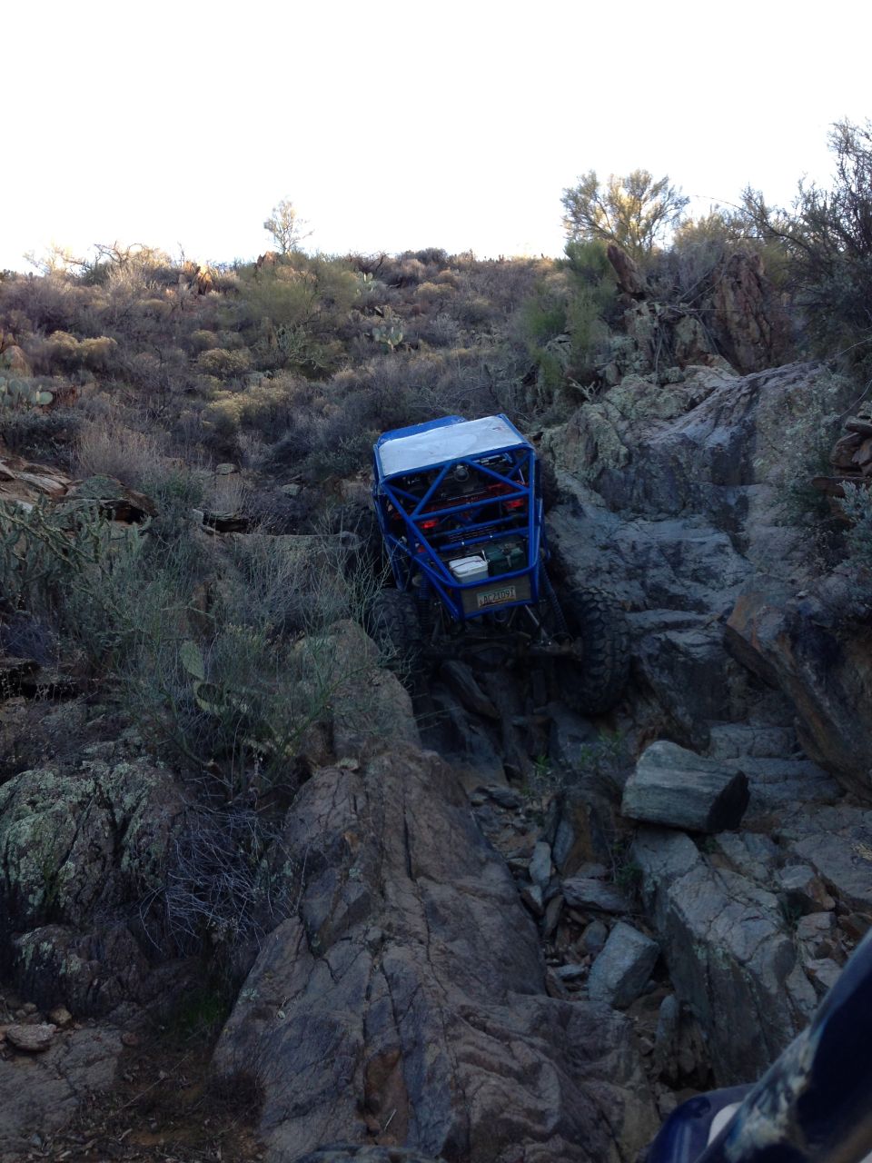 Blue off-road buggy navigating a steep, rocky trail