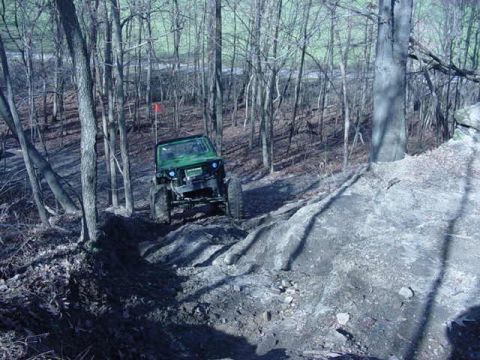 1992 Ford Bronco - Off-road vehicle navigates a challenging dirt trail through a forest.