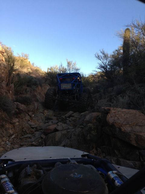 1966 Ford Bronco - Two off-road vehicles navigate a challenging rocky terrain under a clear blue sky.