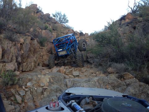 1966 Ford Bronco - A custom off-road buggy navigates a steep, rocky incline in a desert landscape.