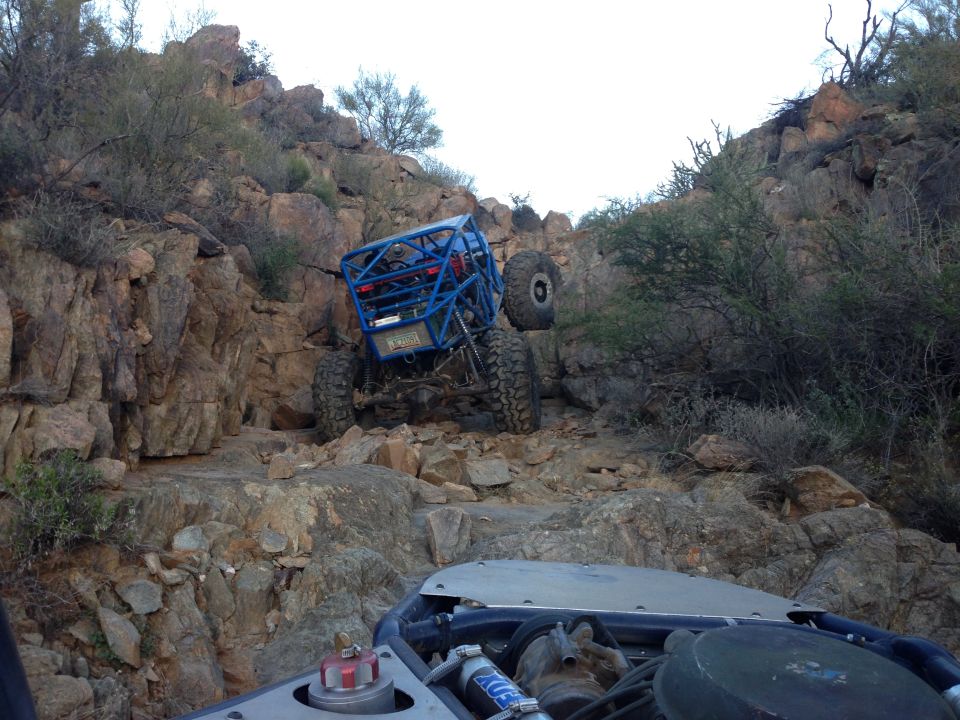 Blue off-road buggy climbing a rocky hill, with another vehicle in the foreground