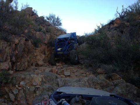 1966 Ford Bronco - Two off-road vehicles navigate a steep, rocky incline in a desert landscape.