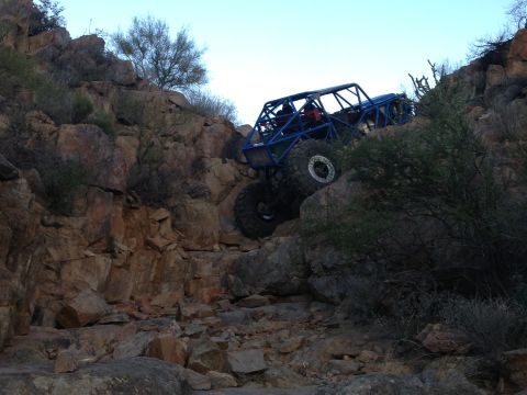 1966 Ford Bronco - Custom off-road buggy navigates a steep, rocky incline in a desert landscape.