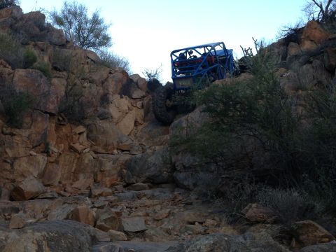 1966 Ford Bronco - A custom off-road buggy navigates a steep, rocky incline in a desert landscape.