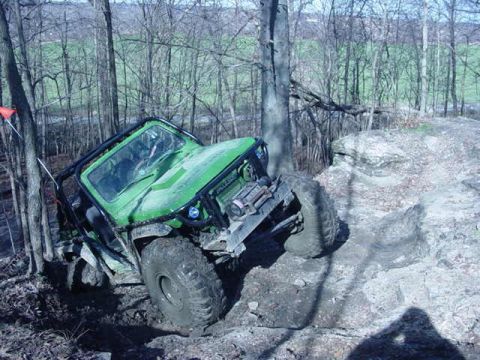 1992 Ford Bronco - This off-road vehicle navigates a challenging rocky terrain in a wooded area.