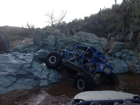 1966 Ford Bronco - Off-road buggy navigates a rocky stream bed in a desert landscape.