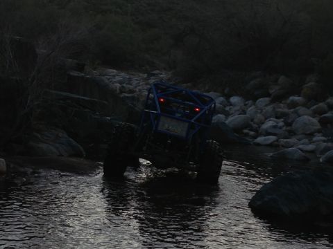 1966 Ford Bronco - Off-road buggy navigates rocky stream bed in low light conditions.