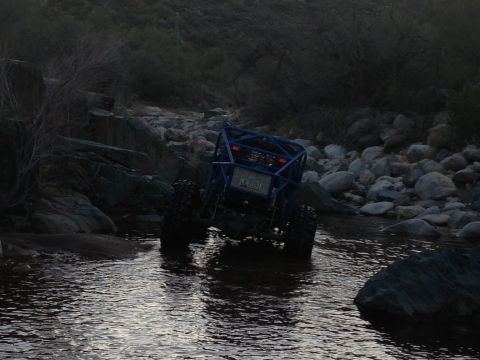 1966 Ford Bronco - A custom-built off-road buggy navigates a shallow, rocky stream in dim lighting.