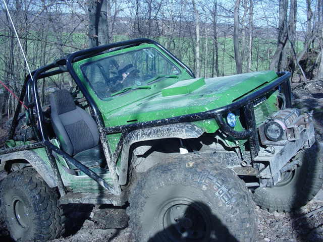 Green off-road vehicle with a roll cage and large tires, angled from the front-right
