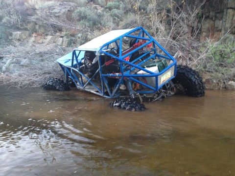 1966 Ford Bronco - An off-road buggy with a roll cage is stuck in a shallow stream bed.