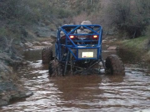 1966 Ford Bronco - A heavily modified off-road buggy navigates a rocky, shallow stream.