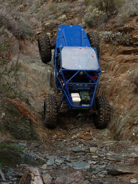 1966 Ford Bronco - A custom-built off-road buggy navigates a steep, rocky incline in a desert environment.