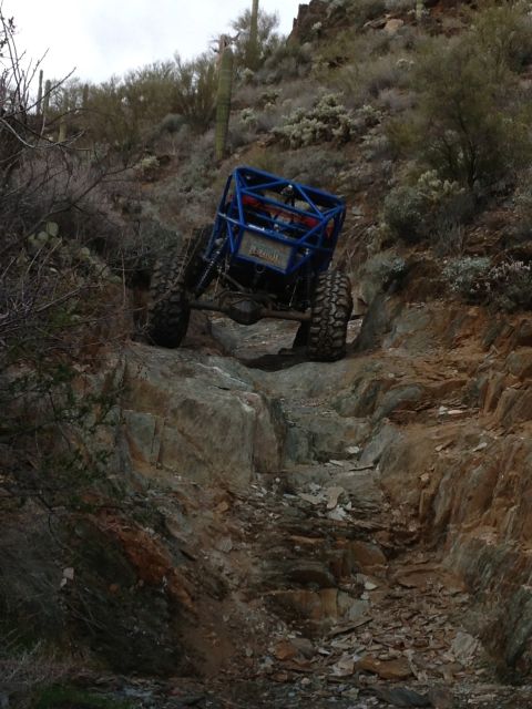 1966 Ford Bronco - Custom blue buggy navigates a challenging rocky incline in a desert environment.