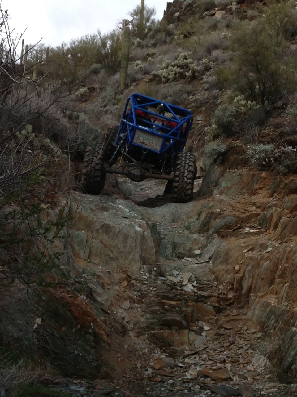 Blue off-road buggy with roll cage climbing steep rocky trail