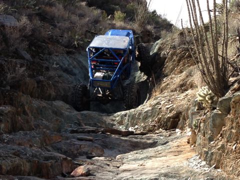 1966 Ford Bronco - A custom off-road buggy navigates a challenging rocky incline in a desert landscape.