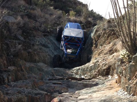 1966 Ford Bronco - Custom off-road buggy navigates a challenging rocky incline in a desert landscape.