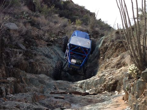 1966 Ford Bronco - A custom blue buggy tackles a challenging rocky terrain, demonstrating extreme off-road capability.