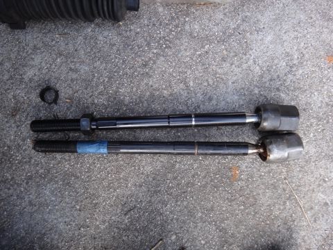 2000 Lincoln Continental - Two automotive tie rods are laid out on a grey asphalt surface for comparison.