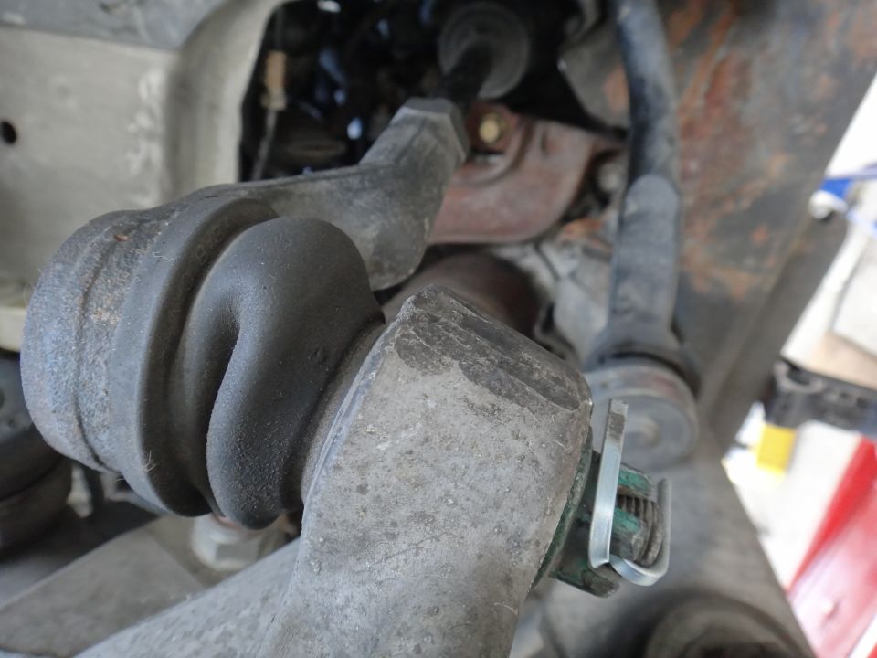 close-up of car's suspension parts, rubber boot and metal arm visible