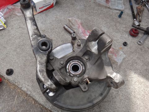 2000 Lincoln Continental - Suspension components including knuckle, control arm, and brake rotor laid out on a concrete surface.