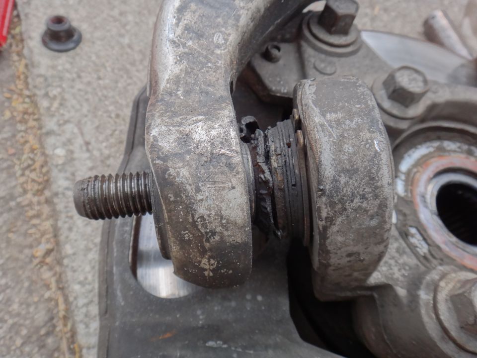 close-up of a damaged suspension bushing with a bolt threaded through it