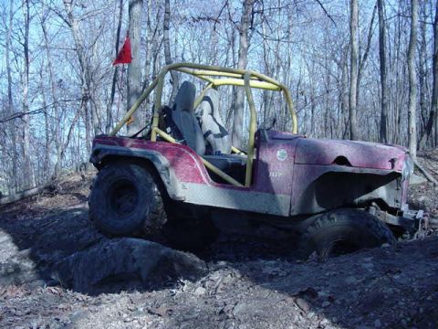 1992 Ford Bronco - Off-road Jeep navigating a challenging rocky terrain with its front wheel caught on a boulder.