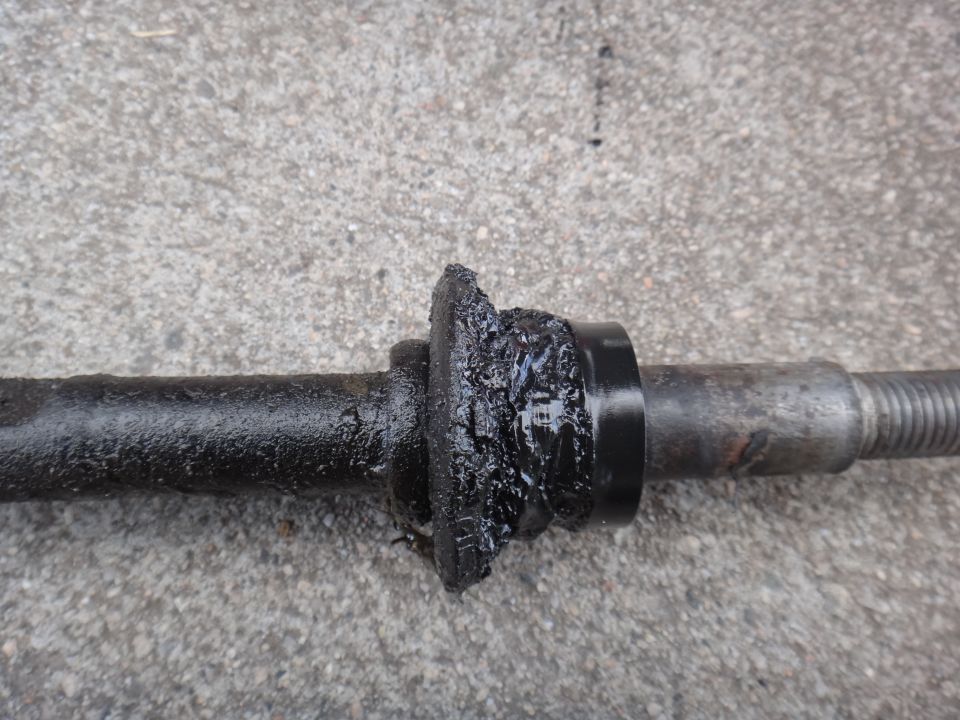 Close-up of a damaged, greased suspension bushing on a metal rod