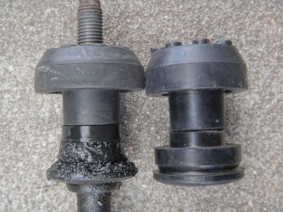 Two black rubber suspension parts, one heavily greased and worn, the other appears new