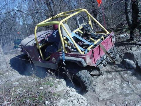 1992 Ford Bronco - This modified Jeep is tackling a challenging off-road course with a second vehicle in the distance.