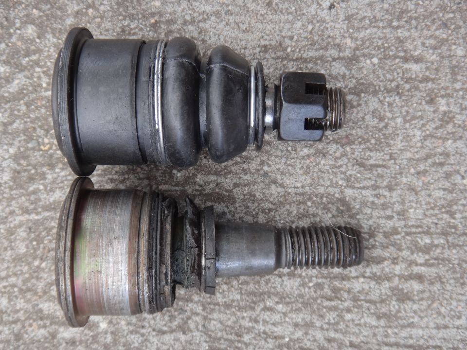 Two ball joints, one new and one worn, on a concrete surface