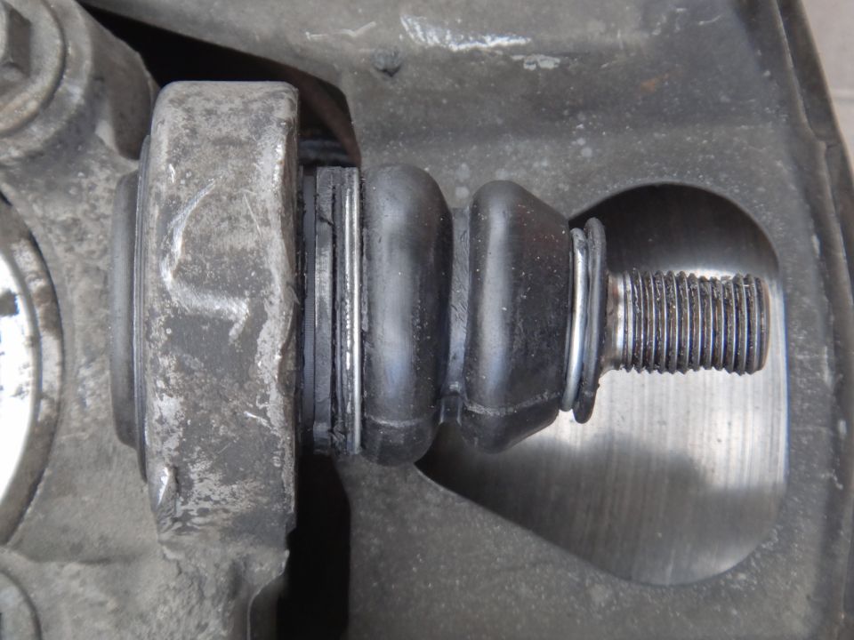 Close-up of a worn suspension part with a rubber boot and metal bolt