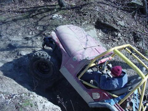 1992 Ford Bronco - A red Jeep navigates a challenging off-road course with a driver focused on the trail ahead.