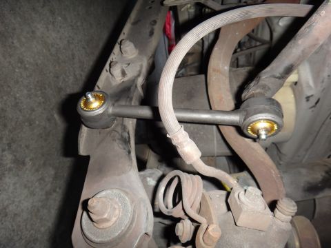 2000 Lincoln Continental - Close-up view of a car's suspension linkage, showing a ribbed brake hose and gold-accented end links.