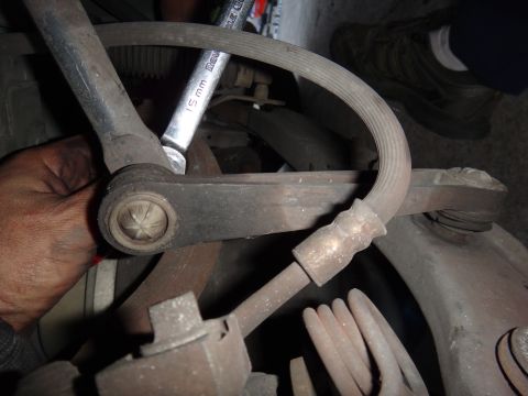 2000 Lincoln Continental - Mechanic uses a 15mm wrench on a vehicle's suspension linkage, focusing on a ball joint assembly.