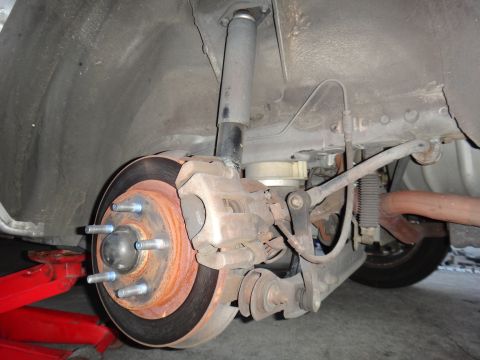 2000 Lincoln Continental - Close-up of a vehicle's rear suspension and brake system, with a red jack underneath.
