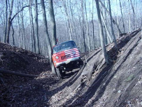1992 Ford Bronco - Off-road vehicle navigating a challenging incline in a dense forest.