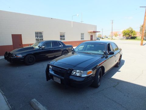 2003 Ford Crown Victoria - Front three-quarter view of a black Crown Victoria, push bar removed, parked near a matte-black twin.