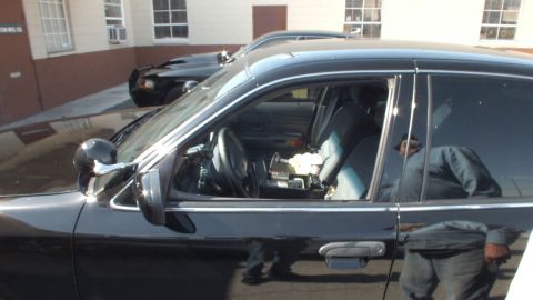 2003 Ford Crown Victoria - Cabin of a black Crown Victoria seen through side windows, with cloth seats and console electronics.